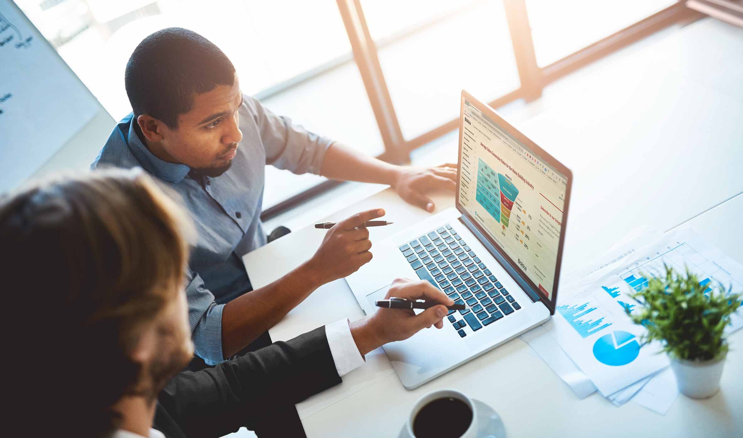 2 marketing professionals looking at computer screen with sales funnel conversions