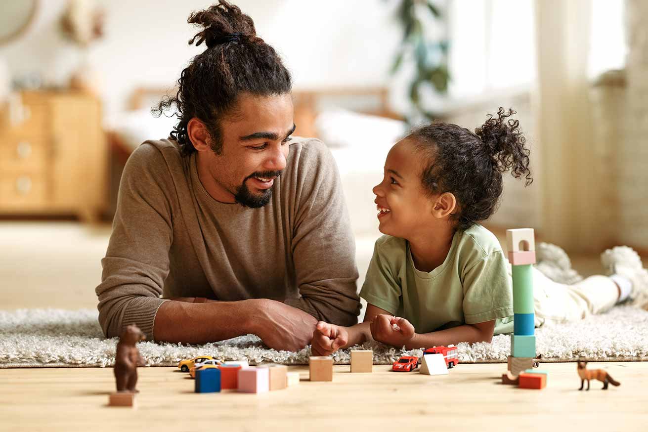 African American man playing happily with his son on the floor