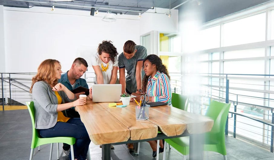 Home builder team gathering around a laptop reviewing blog strategy