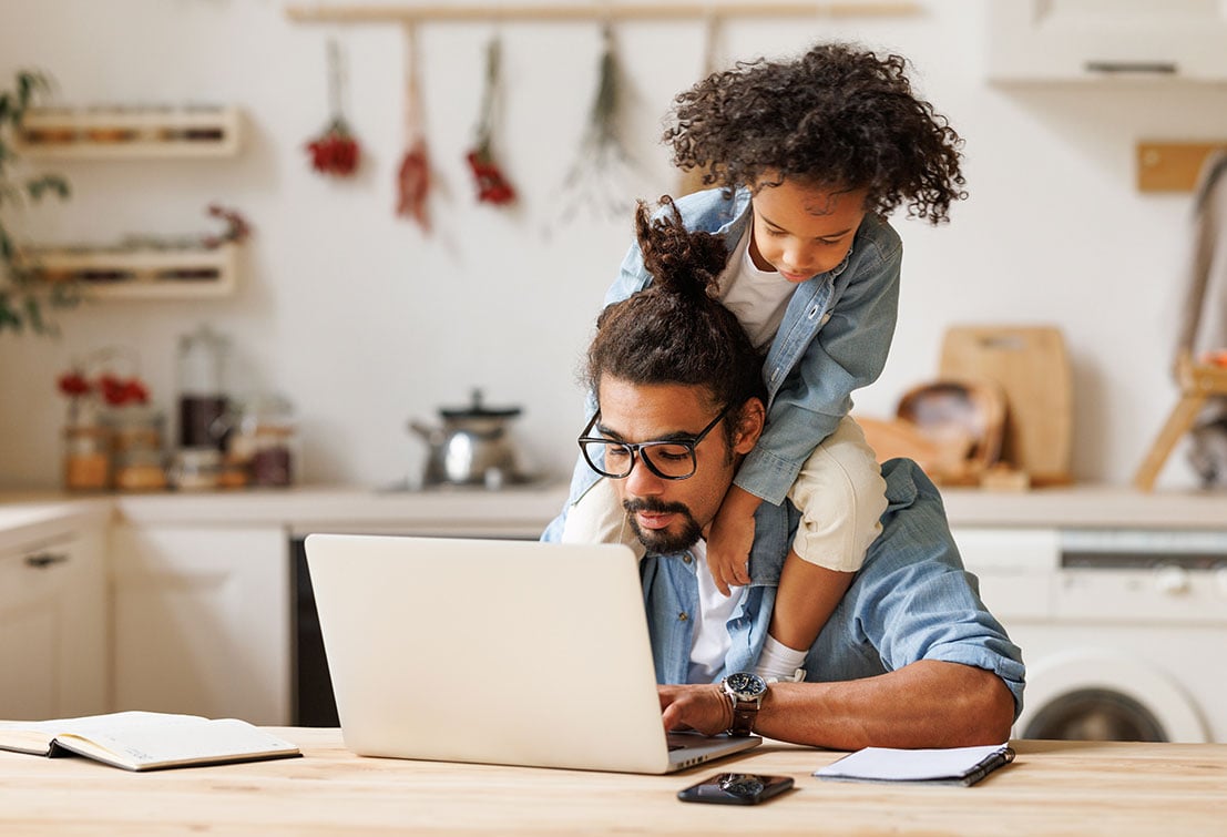 Distracted parent trying to focus on laptop while kid is on his shoulders
