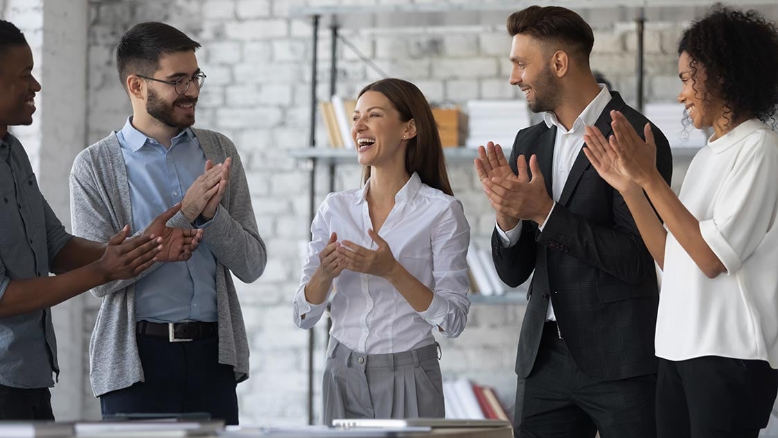 Diverse group of employees at work clapping and smiling