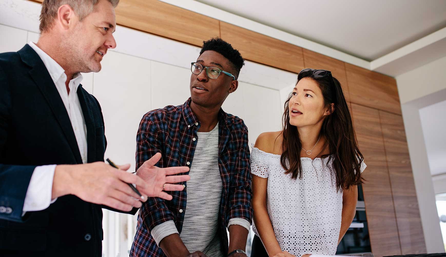 Man in suit selling new construction homes to young interracial couple