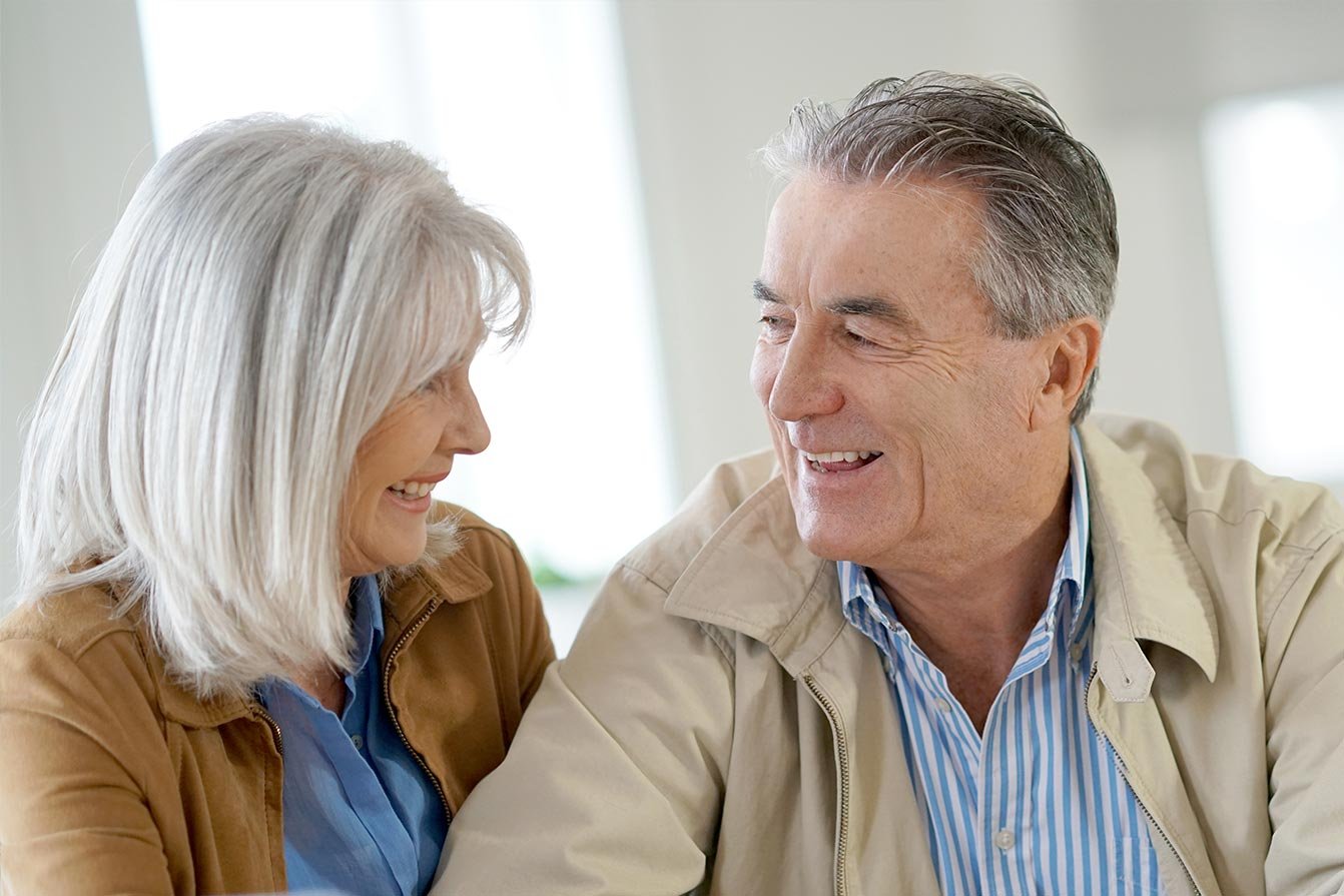 Mature couple smiling while sitting in a sales office