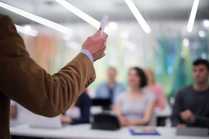 Professor teaching the basics of new construction sales to a classroom of adults