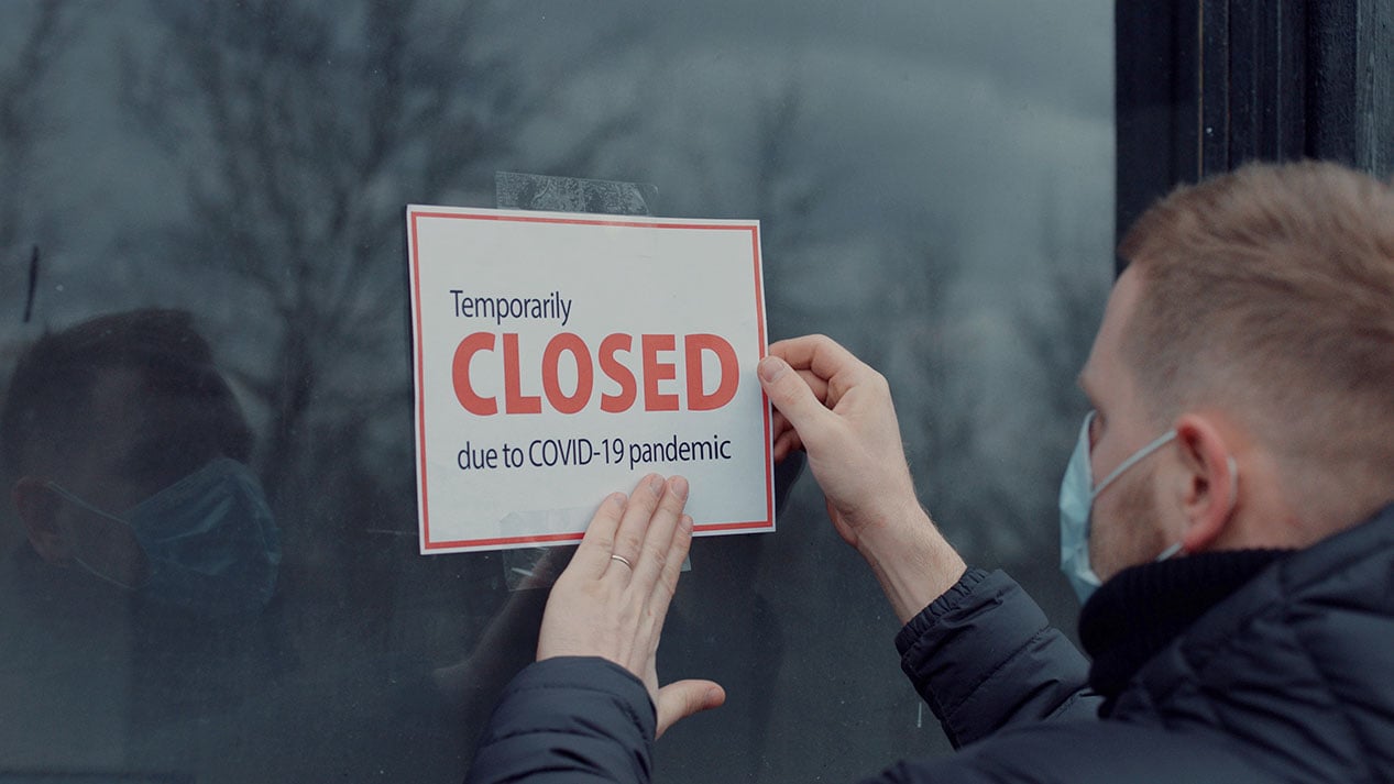 Sales agent at home sales office putting closed sign on window