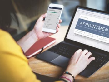 Woman-on-laptop-and-phone-booking-an-appointment-with-a-home-builder