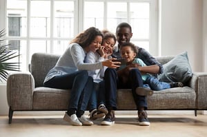 family sitting on sofa watching a virtual new home tour